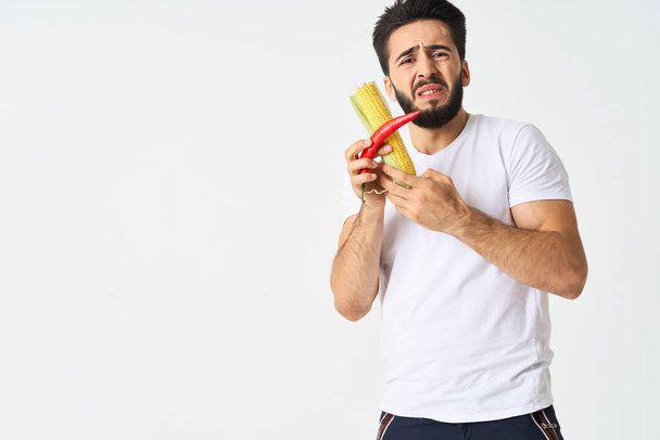 bearded man with vegetables in his hands hot pepper corn - Photo, Image
