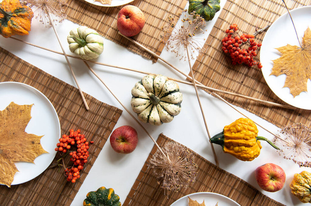 colocação plana de pequenas abóboras e folhas de bordo marrom seco em placas brancas, decorações de mesa de jantar de outono - Foto, Imagem