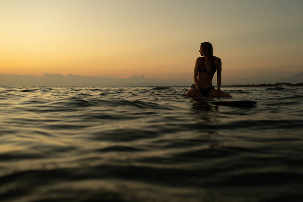 beautiful girl with a surfboard at sunset. high quality photo - Foto, Imagen