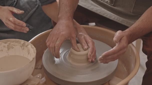 Korkea-kulma lähikuva miesten ja naisten kädet työskentelevät keramiikka pyörän keitto savi potin työpaja - Materiaali, video