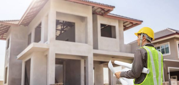 молодий професійний інженер в захисному шоломі і кресленнях паперу на будівельному майданчику будинку
 - Фото, зображення