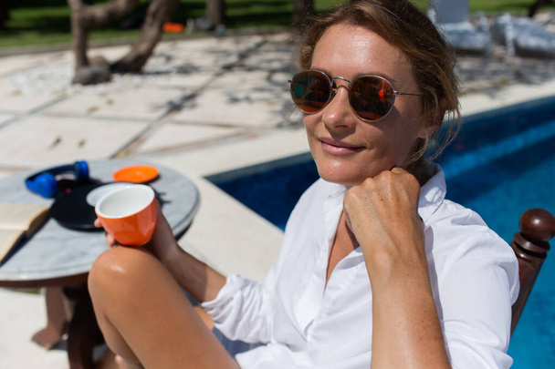 プールの近くでコーヒーを飲む美しい女性。高品質の写真 - 写真・画像