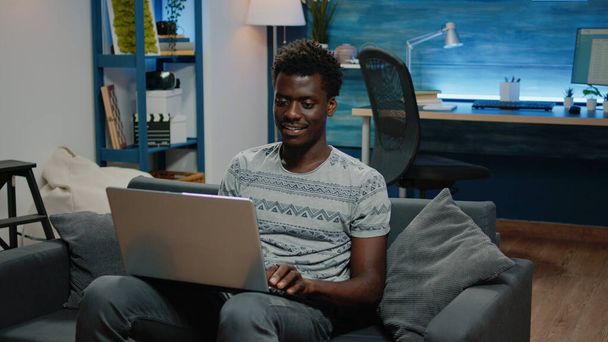 Επιχειρηματίας χρησιμοποιώντας φορητό υπολογιστή για απομακρυσμένη εργασία, ενώ κάθεται στον καναπέ - Φωτογραφία, εικόνα