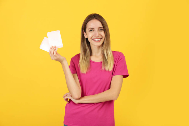 Happy young woman with disposable menstrual pads on yellow background - Foto, Bild