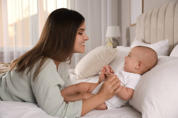 Young woman with her little baby on bed at home - Foto, Imagen