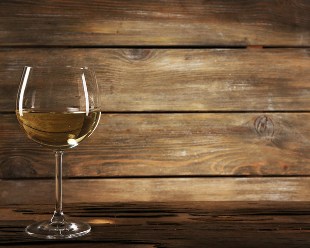 Goblet of white wine on wooden table on wooden wall background - Фото, зображення