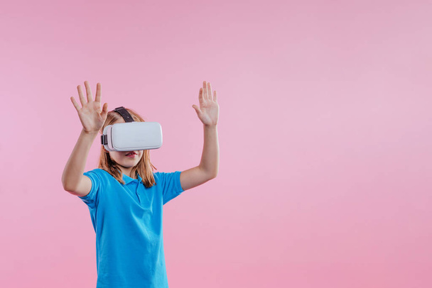 Έφηβη που φοράει συσκευή εικονικής πραγματικότητας. Πορτραίτο στούντιο σε ροζ φόντο με κενό χώρο για κείμενο - Φωτογραφία, εικόνα