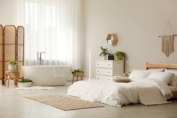 Stylish apartment interior with white bathtub and bed - Zdjęcie, obraz