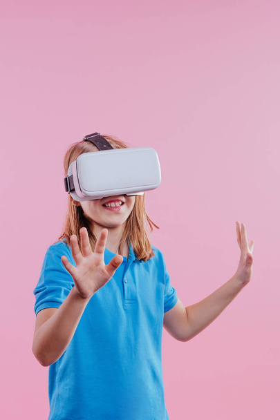Chica adolescente con dispositivo de realidad virtual. Retrato de estudio sobre fondo rosa con espacio en blanco para texto - Foto, imagen