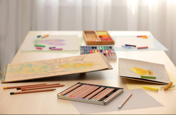 Artist's workplace with drawings, soft pastels and color pencils on table indoors - Valokuva, kuva