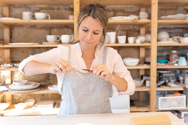 Eine attraktive Kunsthandwerkerin in ihrer schönen Werkstatt - Foto, Bild