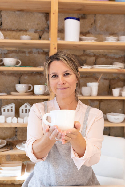 An Attractive professional craftswoman offering a cup of tea or coffee - Photo, Image