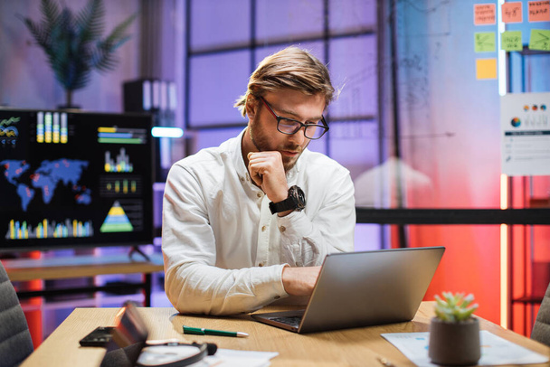 Focused man typing on laptop while sitting at office - Foto, Bild