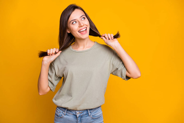 Portrait of pretty cheerful dreamy brown-haired girl having fun making tails looking aside isolated over bright yellow color background. - Foto, Imagen