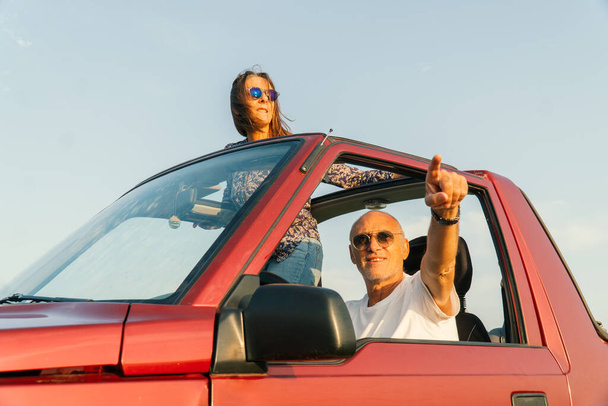 高齢者のカップルは、海を指して、その4 × 4コンバーチブル車で海岸を旅 - 写真・画像