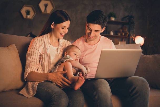 Portrait of attractive cheerful family motherhood fatherhood parenthood rocking toddler using laptop at home house flat indoors. - Fotó, kép