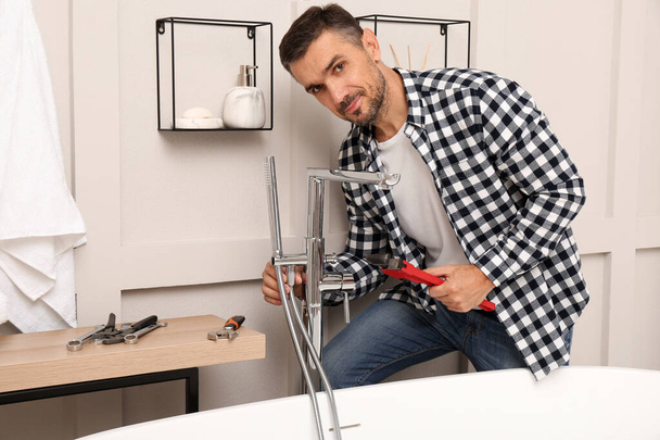 Man installing water tap with shower head in bathroom - Zdjęcie, obraz