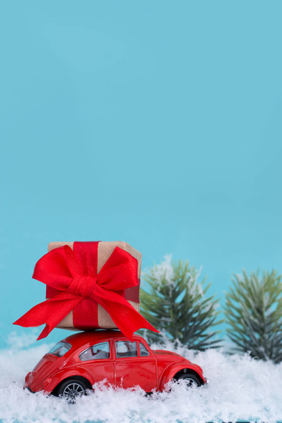 Red retro car with gifts on snow and blue background. The minimalistic style of the New Year's card. - Фото, изображение
