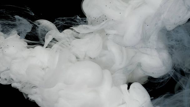 White and blue ink mixed in water on a black background. Milky white background. White cloud of ink, white smoke. Amazing abstract white background. - Фото, изображение