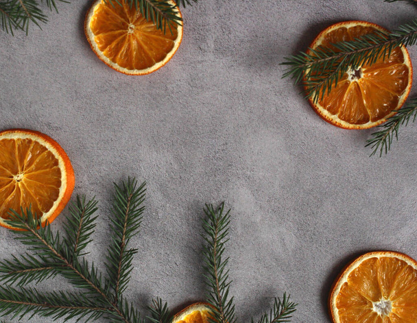 layout on a gray concrete background of orange slices and spruce branches with copy space - Photo, Image