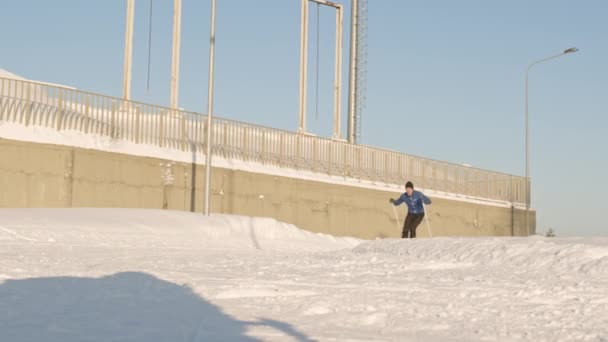 Atrapado de un joven atleta caucásico con ropa deportiva, practicando esquí de fondo rápido haciendo arco sobre nieve blanca al aire libre en un día soleado - Metraje, vídeo