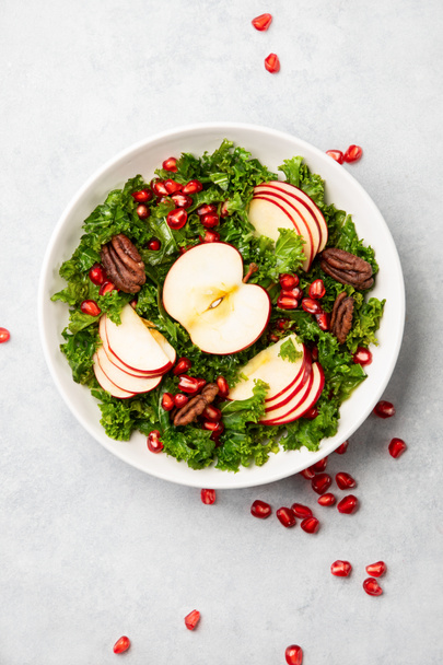 Kale apple and pomegranate salad vegan recipe, top-down view of ready-to-eat meal served in a bowl - Фото, изображение