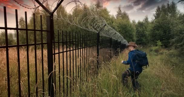 Ο άνθρωπος τρέχει στο φράχτη με αγκαθωτό σύρμα και σκαρφαλώνει πάνω του. Βραδινό ηλιοβασίλεμα - Πλάνα, βίντεο