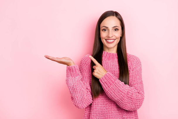 Photo of optimistic young lady hold index empty space wear pink sweater isolated on pastel color background. - Foto, Bild