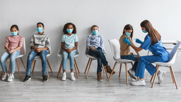 Medische werknemer vrouw vaccineren diverse groep kinderen in de kliniek - Foto, afbeelding