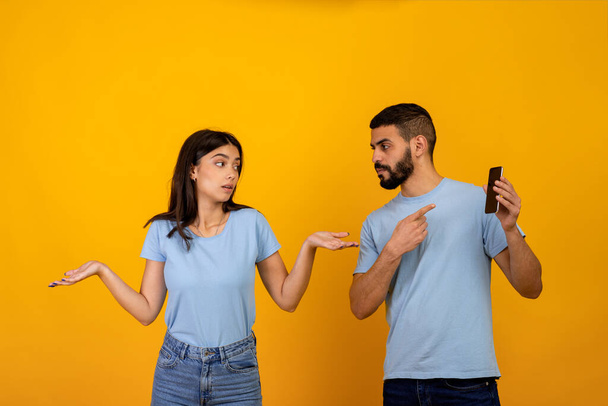 Další online život. Naštvaný arabský muž kontroluje telefon své přítelkyně, ptá se ženy na vysvětlení, dáma roztahuje ruce - Fotografie, Obrázek