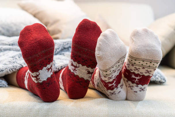 Christmas socks of family couple feet relaxing on couch having good holiday time together, enjoying resting at home in living room for winter Xmas and New Year day celebration - Photo, Image
