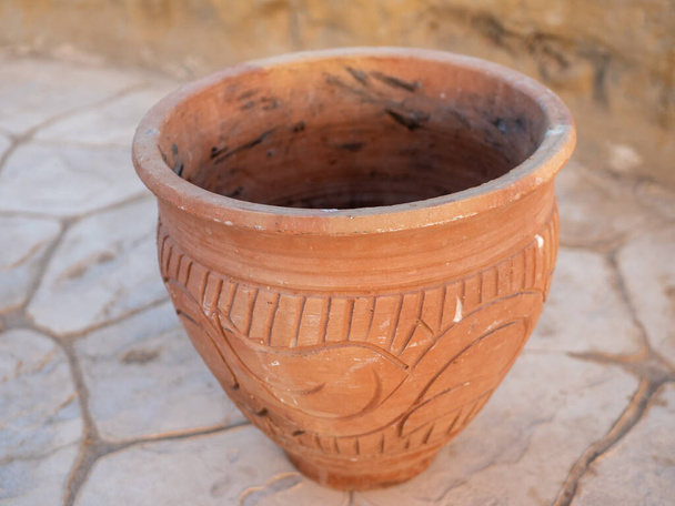 Pot en argile marron avec des ornements se dresse sur le sol en pierre. Gros plan. - Photo, image