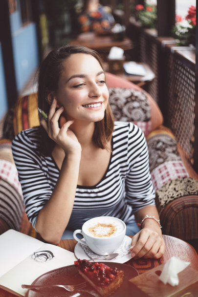 Nuori nainen istuu sisällä kaupunkien kahvilassa
 - Valokuva, kuva