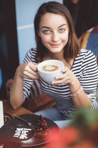 Young woman drinking coffee in urban cafe - Fotografie, Obrázek