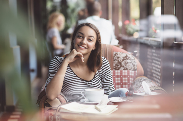 Молода жінка п'є каву в міському кафе
 - Фото, зображення