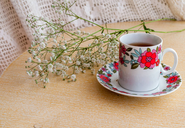 tasse de café sur une table en bois clair avec des fleurs blanches rondes - Photo, image