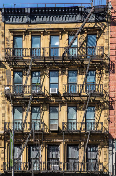 NEW YORK, USA - OCT 5, 2017: σιδερένια σκάλα κινδύνου στην πρόσοψη ενός παλιού ιστορικού σπιτιού στο κέντρο της Νέας Υόρκης. Κάθε σπίτι με 4 και περισσότερους ορόφους χρειαζόταν μια σκάλα κινδύνου από το νόμο.. - Φωτογραφία, εικόνα