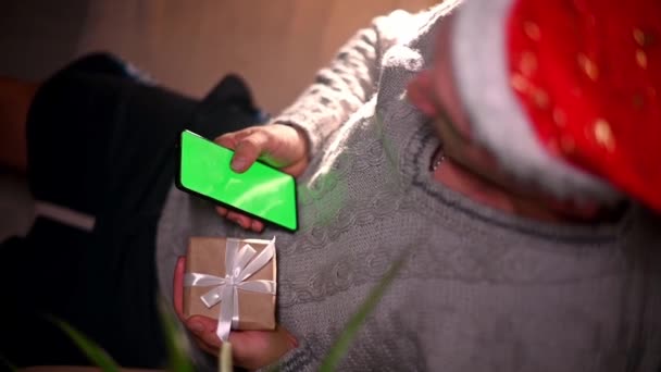 close-up Ένας άνδρας παραγγέλνει ένα δώρο σε ένα ηλεκτρονικό κατάστημα χρησιμοποιώντας ένα smartphone για την οικογένειά του και την αγαπημένη του γυναίκα για τα Χριστούγεννα και την Πρωτοχρονιά. online έννοια αγορών. κλειδί χρωμίου. - Πλάνα, βίντεο