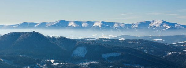 Mountain range covered with snow, on the background of forests and blue sky, winter nature background, Carpathians, Ukraine - Fotó, kép