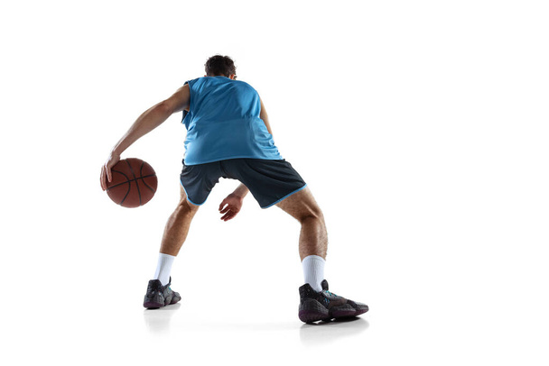 Back view of professional basketball player in blue sports uniform training isolated on white studio background. - Valokuva, kuva