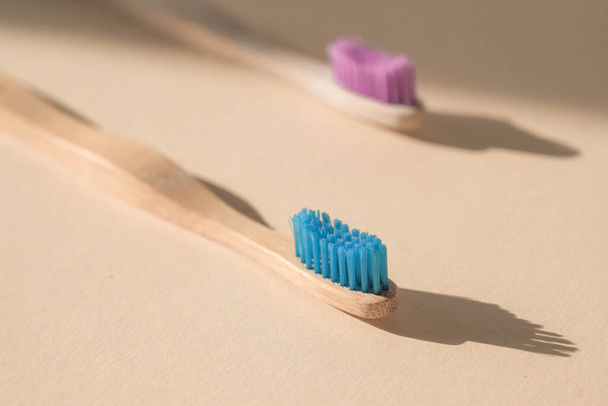 Two Eco-friendly antibacterial toothbrushes made of bamboo wood on a light beige background. Environmental care trends. - Foto, Imagem
