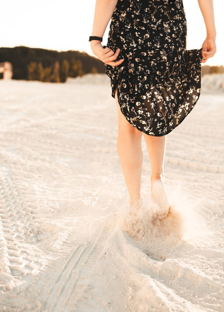 A woman walks barefoot through the sand - 写真・画像