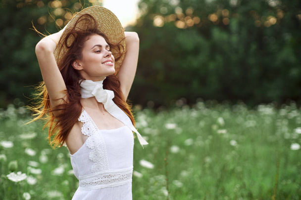 beautiful woman in a hat in a field with flowers walk - Foto, afbeelding