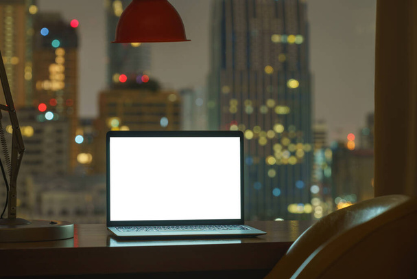 computador portátil na tela branca da tabela ver através da cidade no fundo da noite - Foto, Imagem