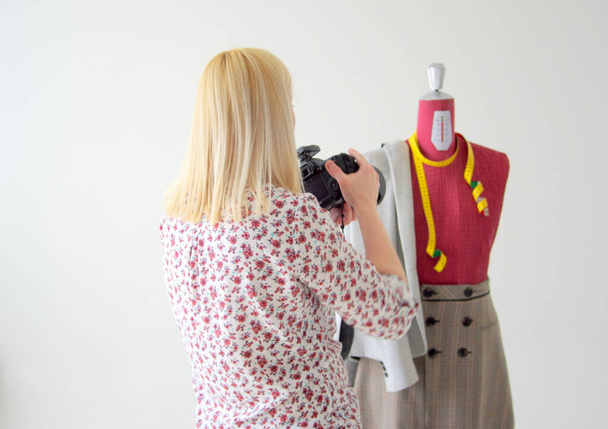A closeup of a blonde female photographer taking pictures of a mannequin - 写真・画像