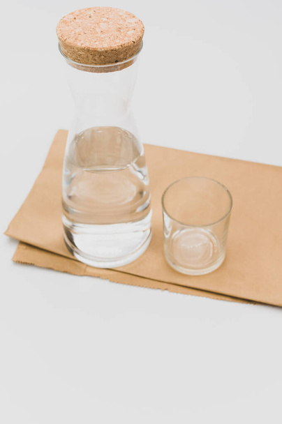 kolba szklana wypełniona czystą wodą na białym i papierowym tle z przestrzenią tekstową - Zdjęcie, obraz