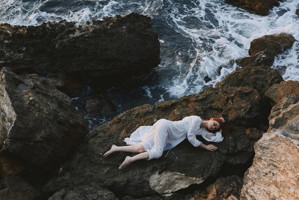 Mezítláb nő fehér ruhában feküdt egy kövön fehér ruhában természet - Fotó, kép