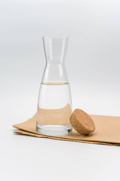 glass flask filled with pure clean water on a white and food paper background with text space - Zdjęcie, obraz