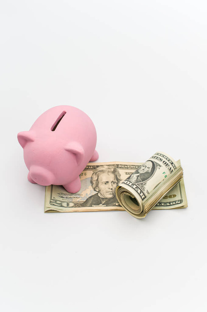 a cute pink piggy bank with a banknotes wad on a white tabletop with copy space - Foto, Bild