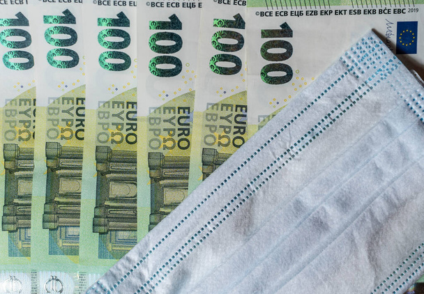 Een medisch masker op 100 euro biljetten. Selectieve focus. 100 euro vaccinstimuleringsconcept. Cadeau voor vaccinatie tegen COVID-19 - Foto, afbeelding